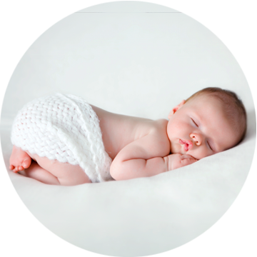 Śpiący noworodek na białym prześcieradle.