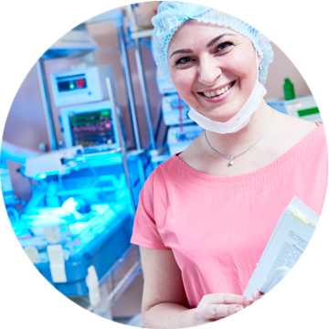 Uśmiechnięta pracownica medyczna w czepku i maseczce na tle oddziału noworodkowego z inkubatorami.