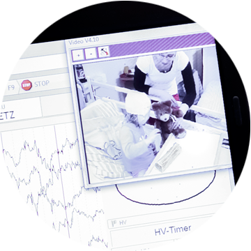 Małe dziecko z założonym profesjonalnym czepkiem do badania EEG uśmiecha się podczas diagnostyki.